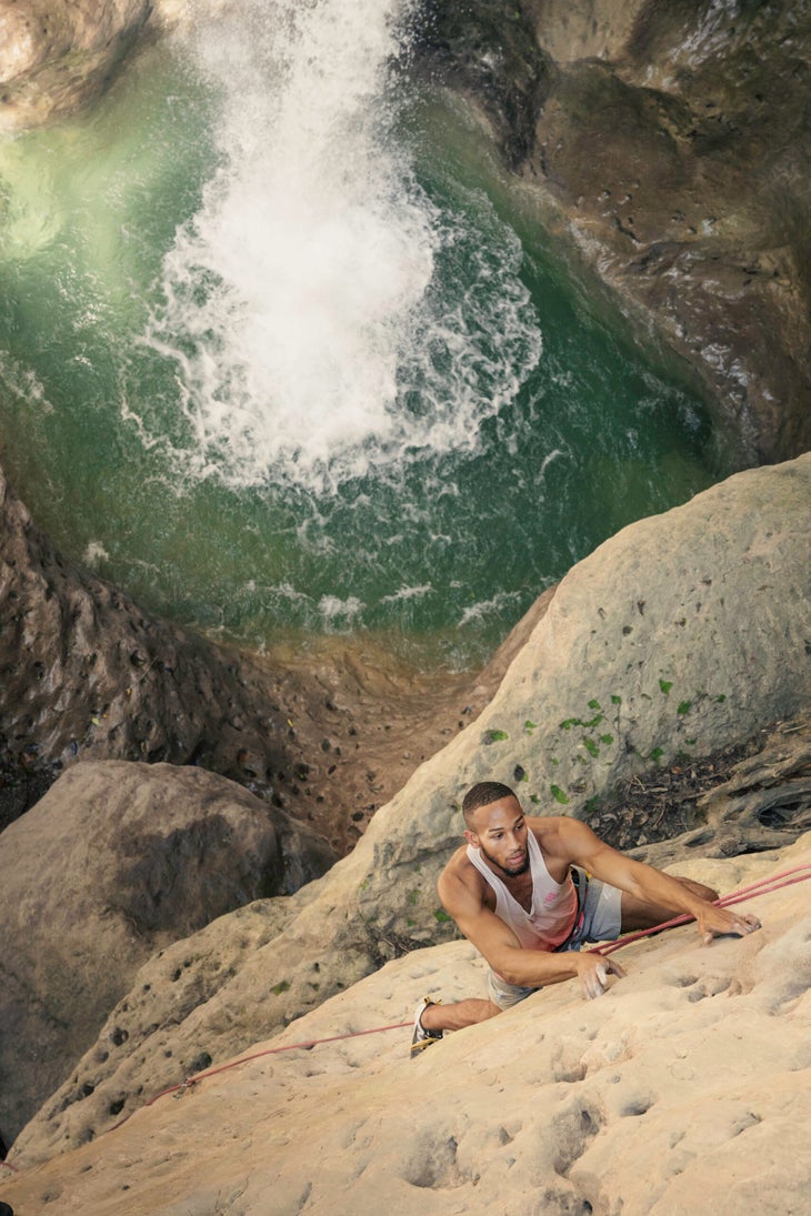 A professional climber climbing above a waterfall in Jamaica