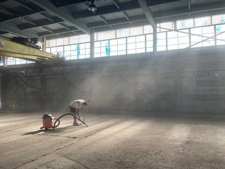 A man vacuuming GP81's dusty new climbing gym space