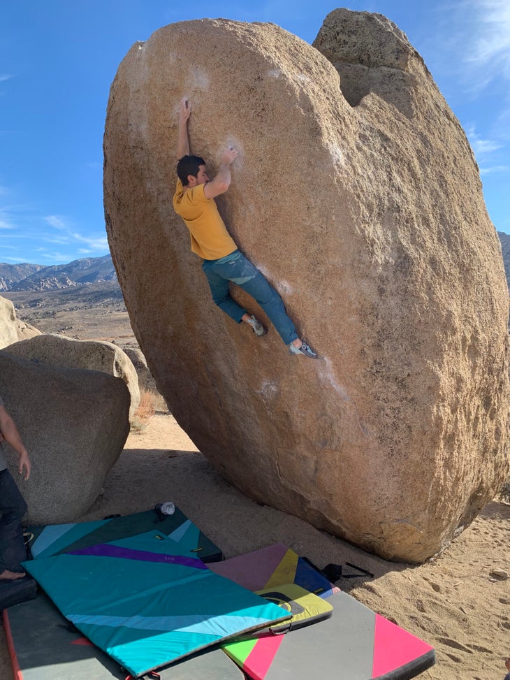 The author climbing a crimpy, egg-shaped boulder in California.