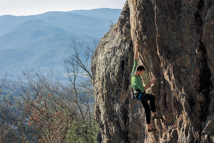 Man climbs overhanging rock wall in New Hampshire.