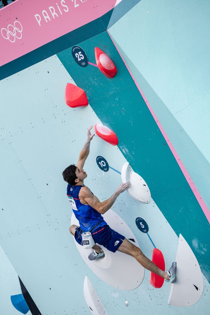 Jesse Grupper high on Men's 2 in the boulder semi-final. He's got a right hand undercling/sidepull, a left foot heel, and is crossing to a terrible red sloper.