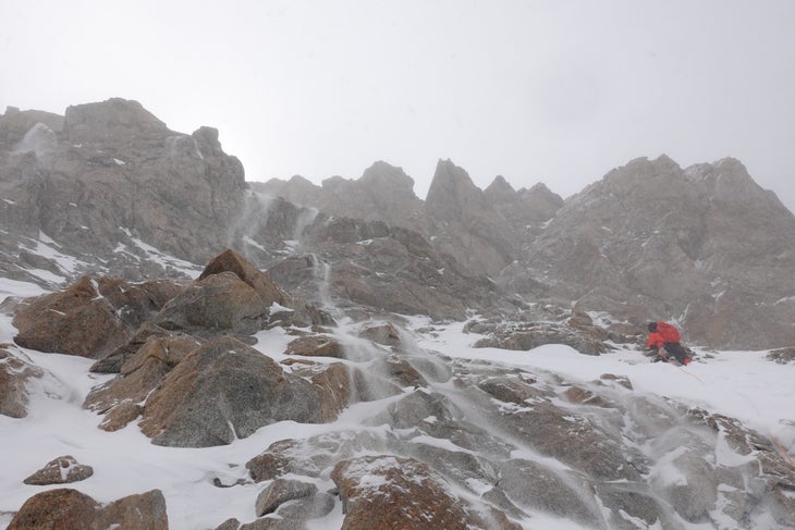 A climber moving through spindrift high on the west ridge of Gasherbrum III