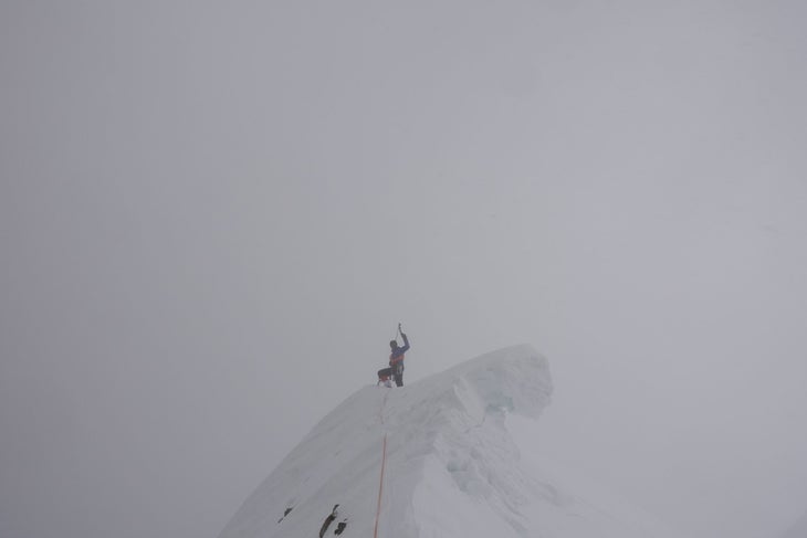 A climber standing on the misty summit of Gasherbrum III