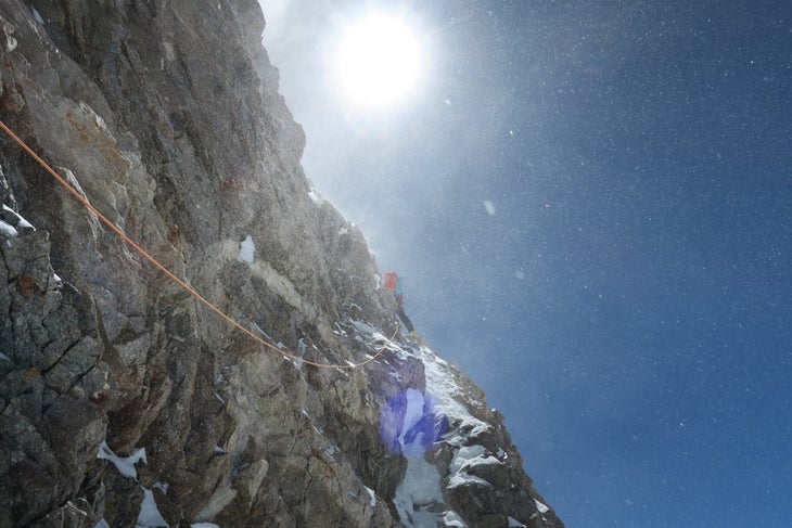 A climber very runout on a steep mixed snow and rock cliff.