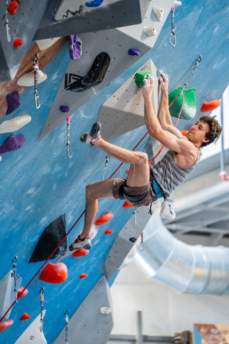 Jesse Grupper doing a hard move on a lead climbing well. His tongue is sticking out from between his pursed lips.