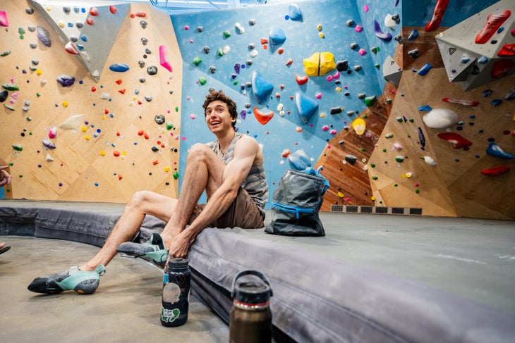 U.S. Olympian Sport Climber Jesse Grupper smiling as he pulls on his shoes for a during a training day in his local gym.