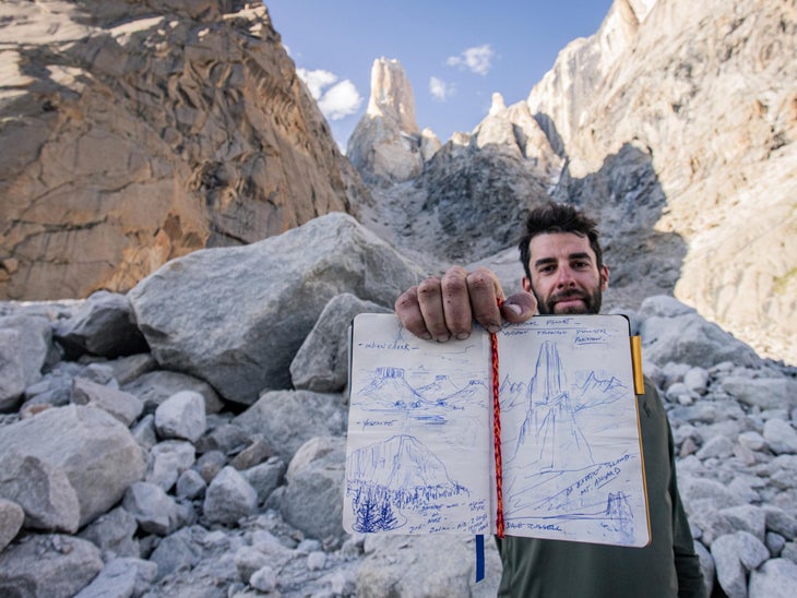 Climber poses below tower with a hand drawn map of the route.