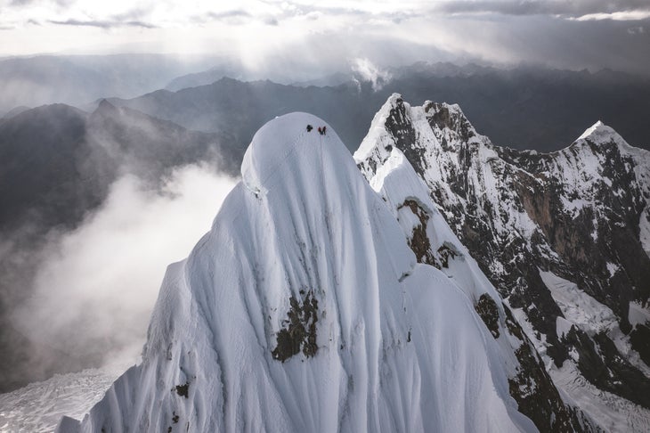 Four climbers stand on the summit of a remote Peruvian mountain.