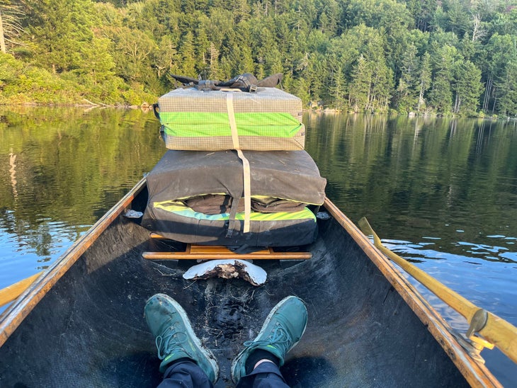 Two bouldering pads in the back of an Adirondack guidebook while the author rows.