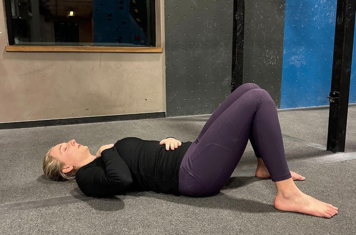 Woman practices diaphragmatic breathing and abdominal contractions to help return to climbing after pregnancy.