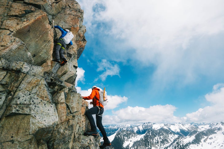 Two climbers scramble in the Tantalus Mountains wearing the new Alpha SL backpack.