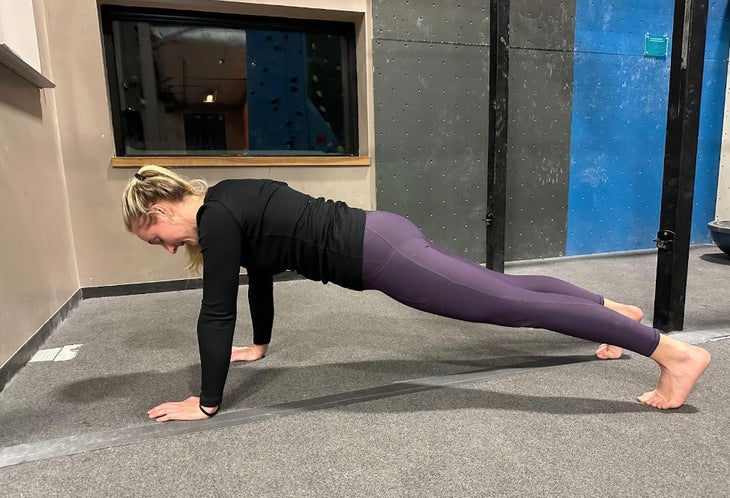 Woman practices front planks to help return to climbing after pregnancy.