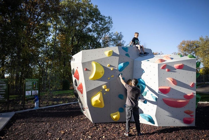 A child on top of an artificial boulder problem.