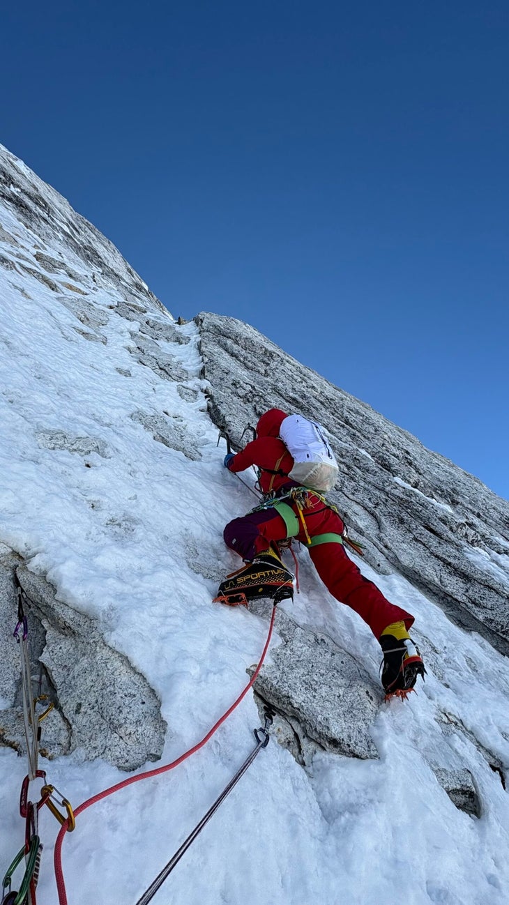 A climber in red ascends steep mixed terrain on the first ascent of Pholesobi, Himalaya.