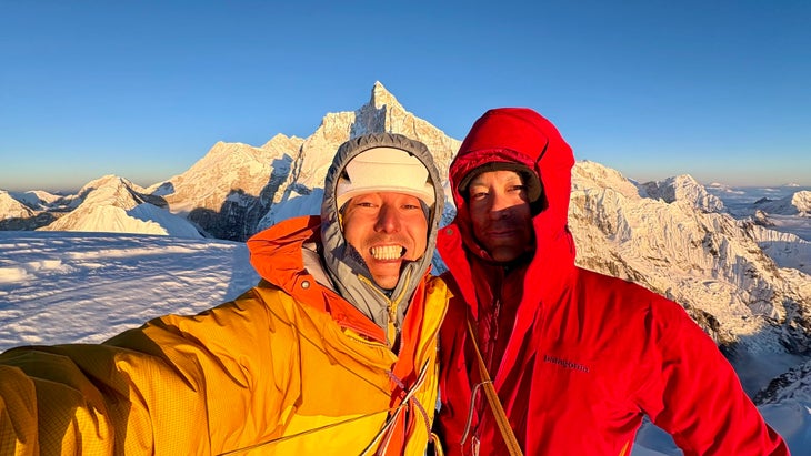 Two smiling climbers post on the summit at sunset after the first ascent of Pholesobi, Himalaya.