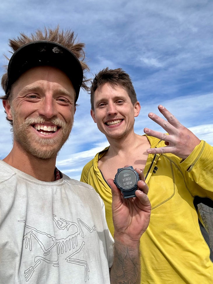 Tanner Wanish and Michael Vaill: Tanner's holding a watch with their activity time recorded. Vaill is holding up four fingers to signify the number of walls they'd climbed.