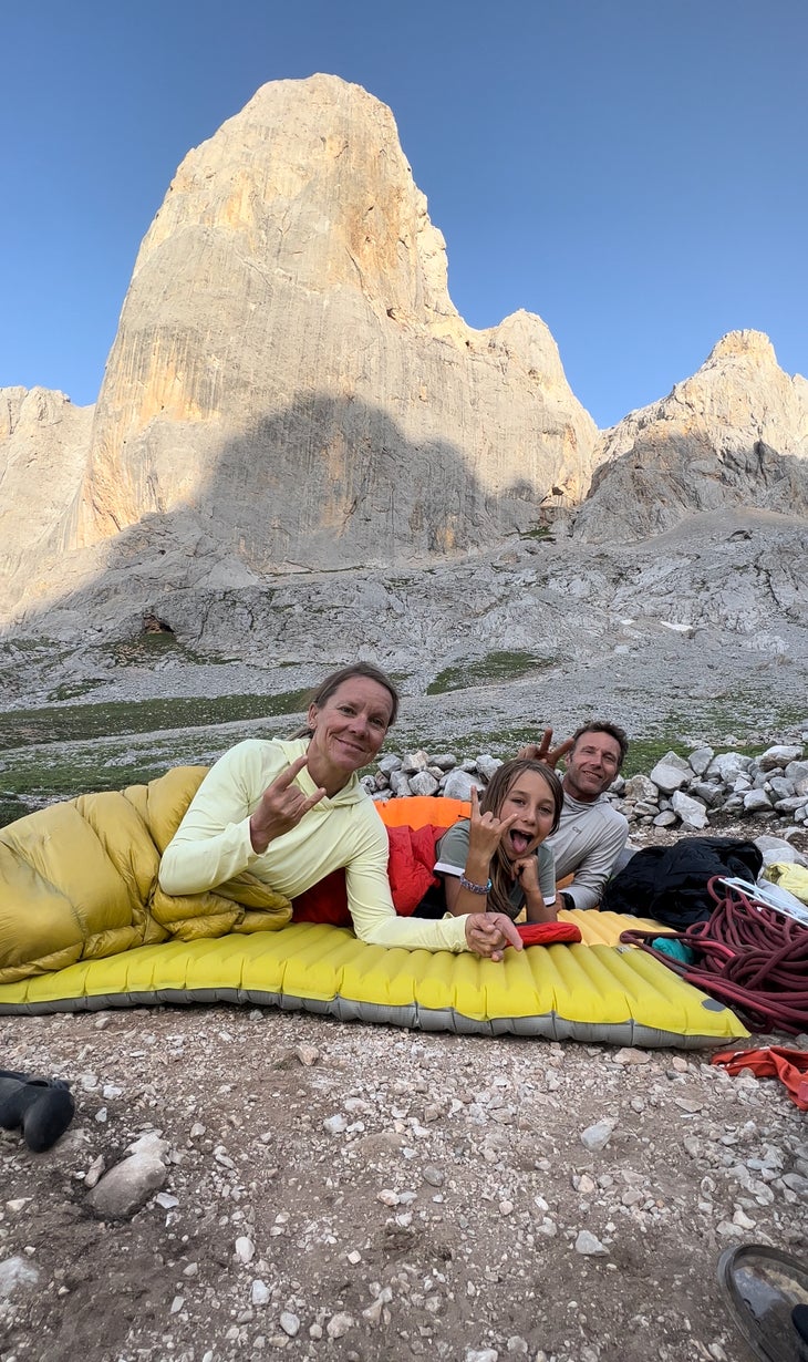 Adam George and his wife and daughter camping below a gigantic limestone cliff.