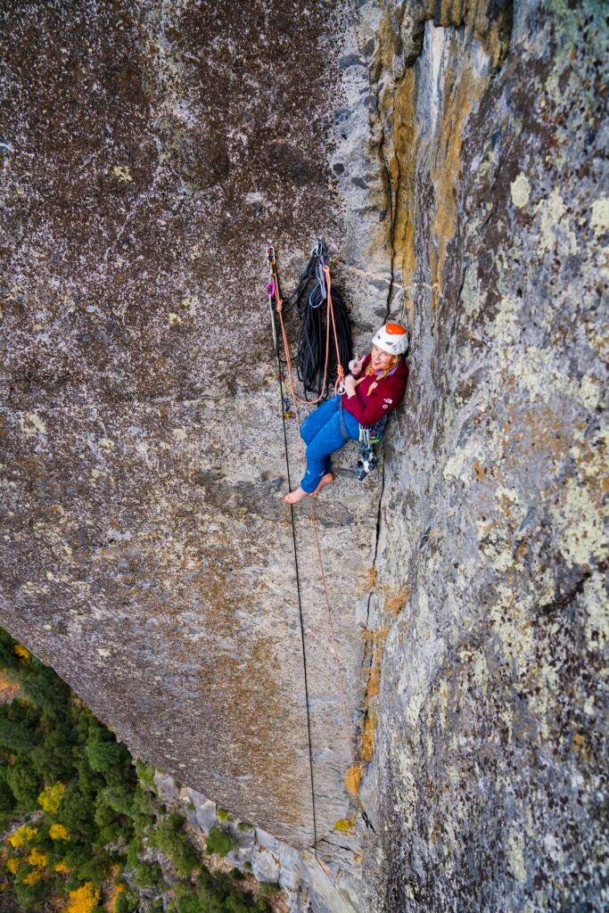 A climber sitting by an anchor on a big wall