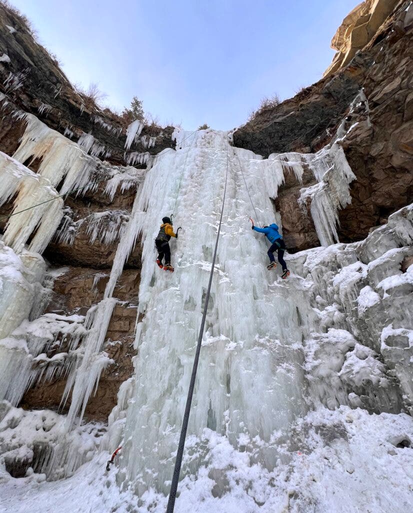two climbers climbing a frozen waterfall