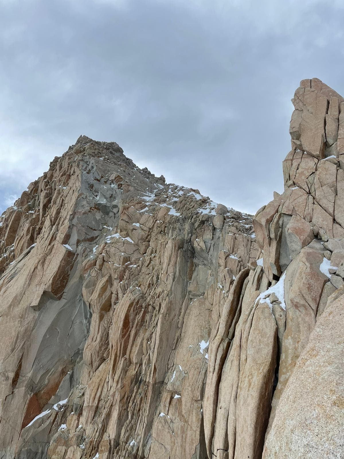 Looking up at a serrated granite ridge in Patagonia, on a cloudy day.