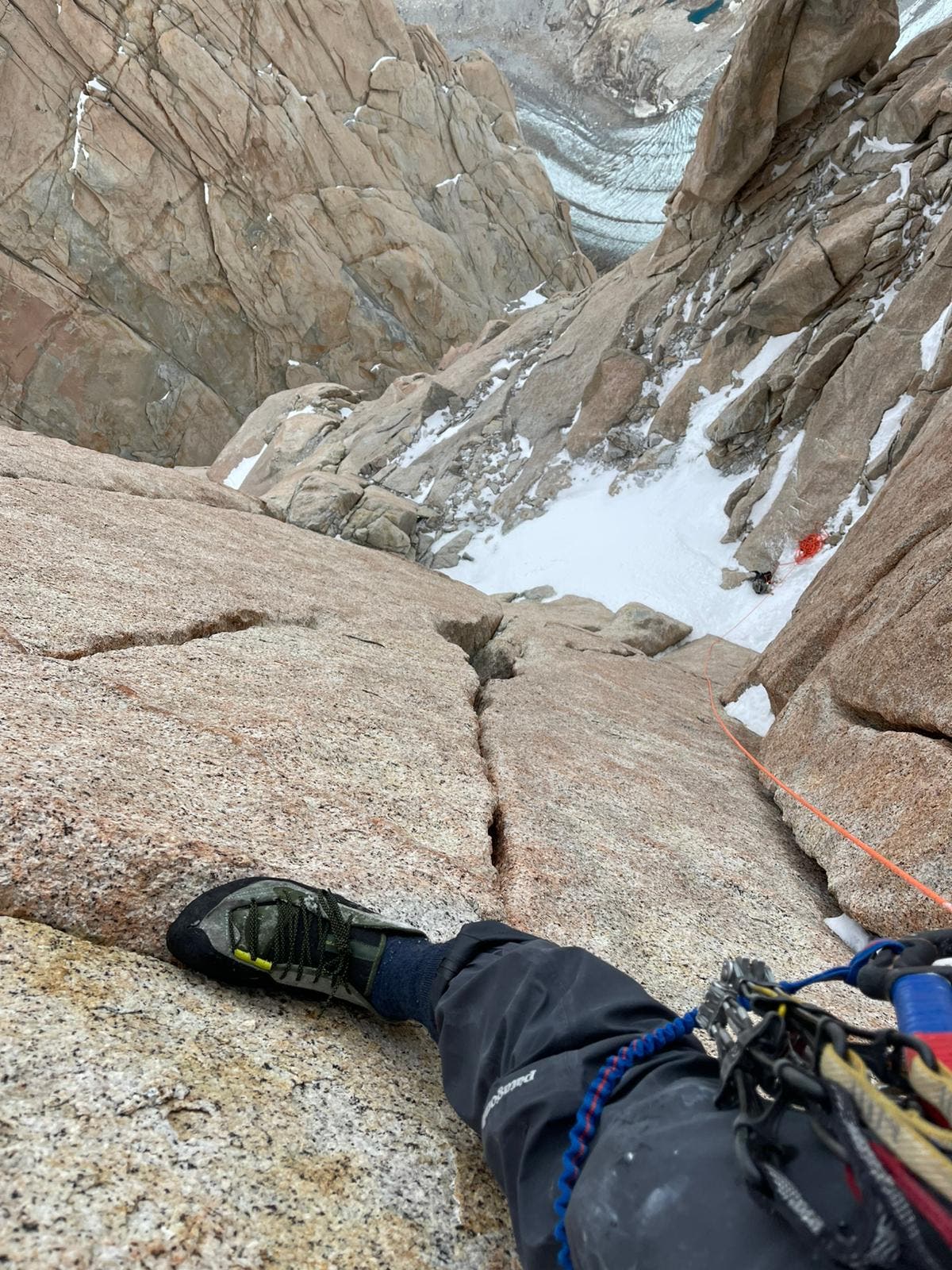 A solo climber takes a photo of their feet against a steep granite wall in Patagonia.