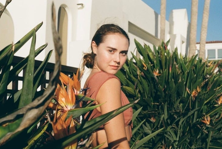Climber Margo Hayes smiles among long grass at sunset.