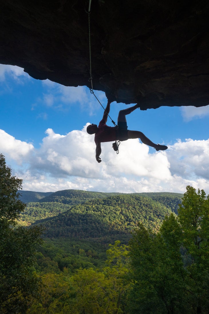 A man climbs a steep roof on a sunny day in Arkansas.