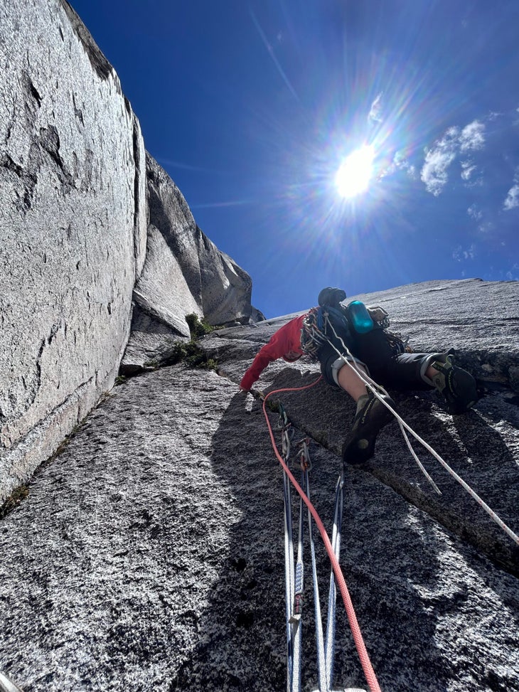 Woman climbs a granite wall on a sunny day in Patagonia.