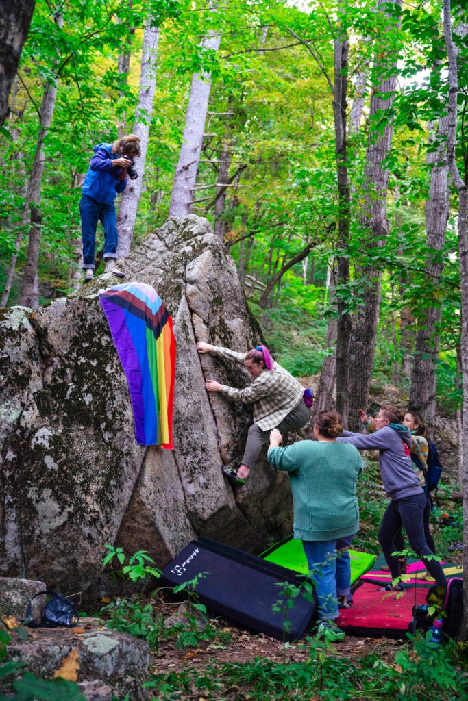 boulderers in the forest with a rainbow flag