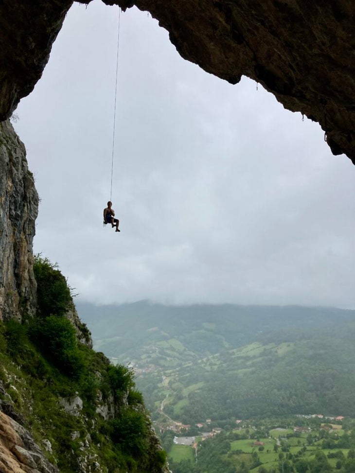 a man dangling from a cave 