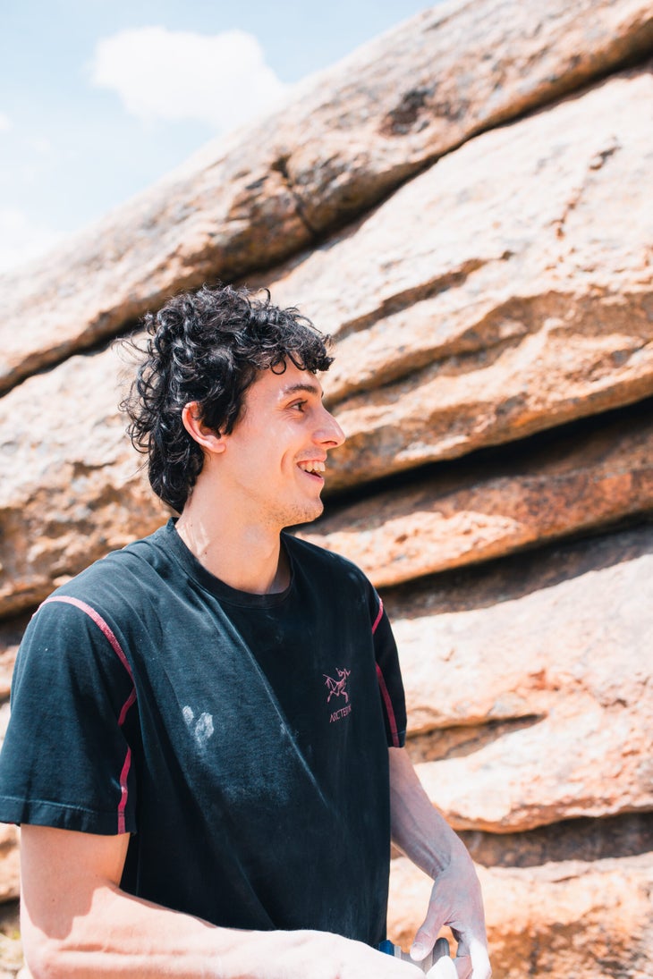 Man smiles after climb a V17 boulder.