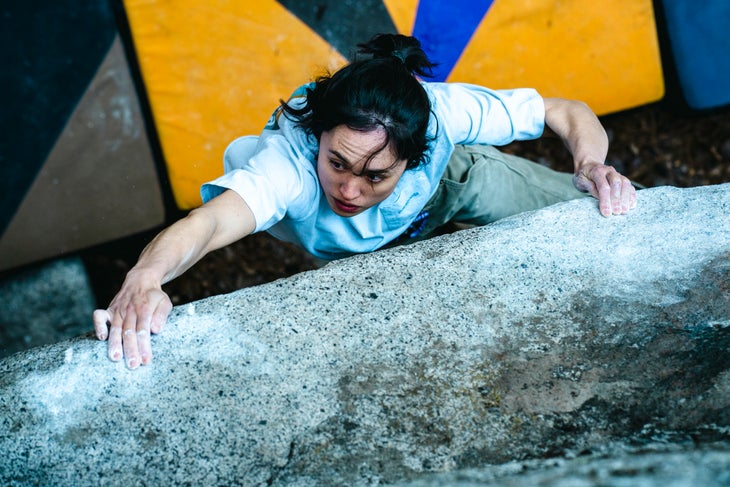 Woman grabs the sloper rail of The Dark Side boulder (V16).