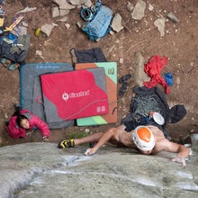 man climbing with bouldering pads below
