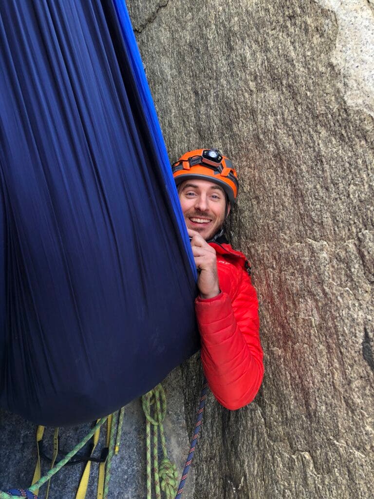 a climber in a hammock on the wall 
