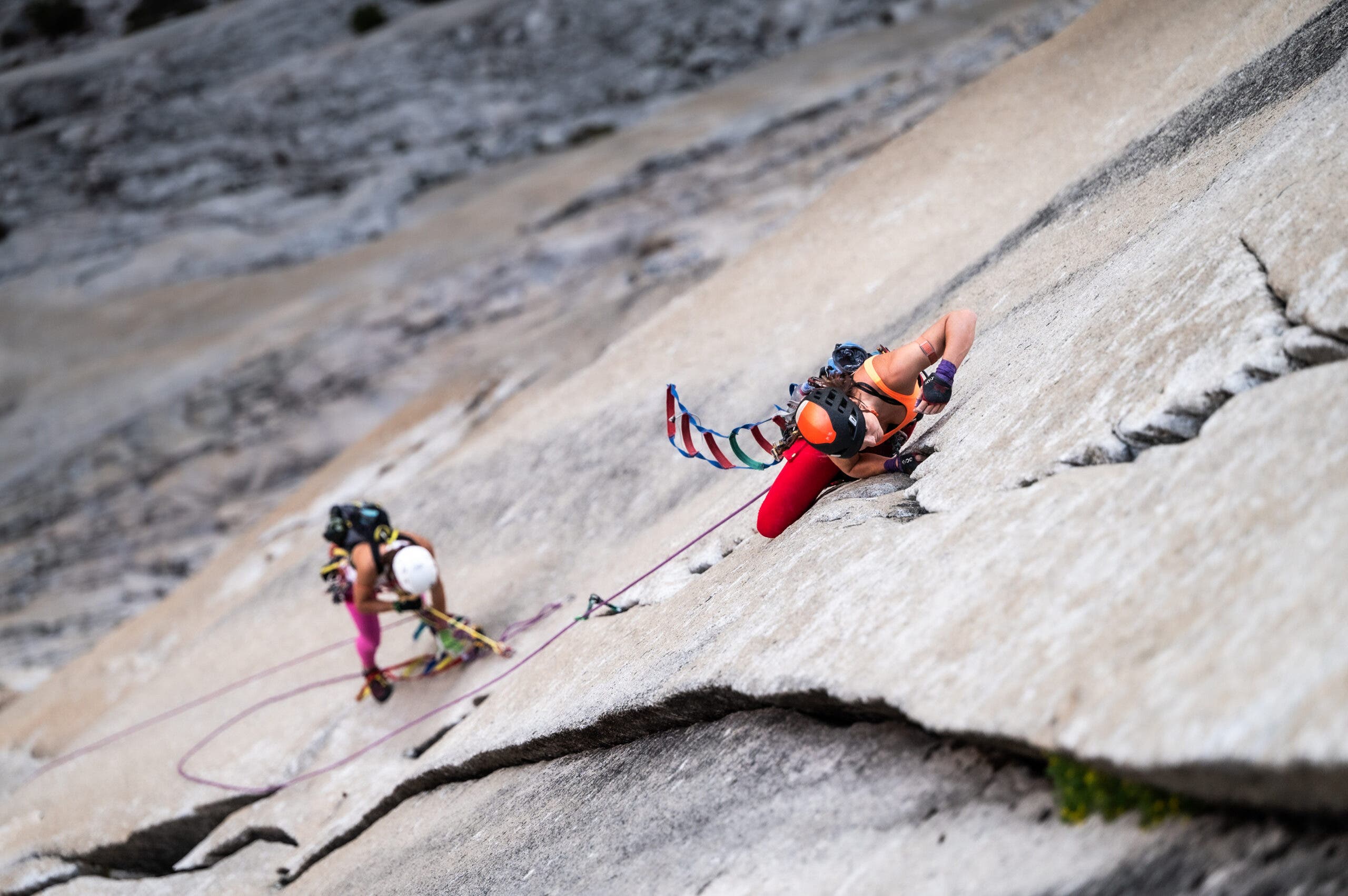 two women climbing up a granite face