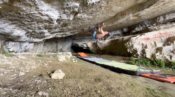 Man climbs V14 boulder in French cave.