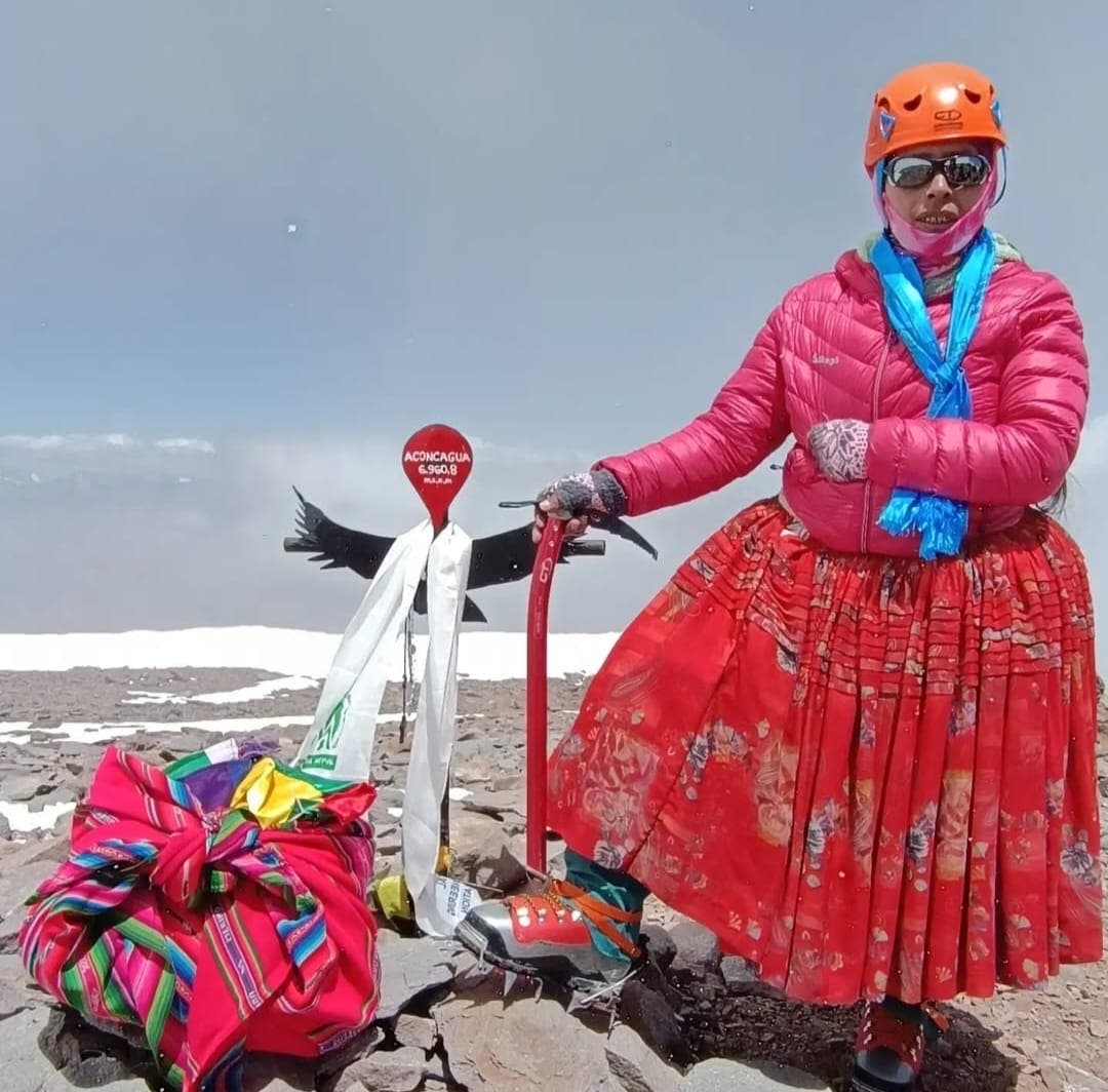 a climbing cholita on the summit of Aconcagua