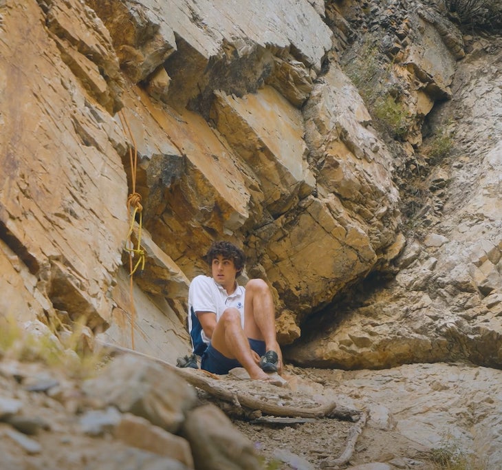 Lincoln Knowles ties his shoes before free soloing the cliff behind him.