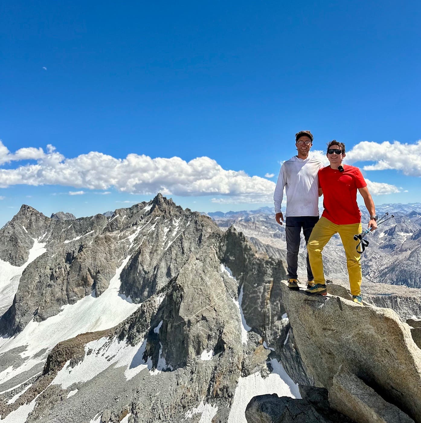 Two men smile on a sunny day atop a mountain in California.