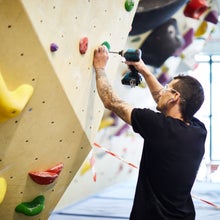 a routesetter drills a hole in at a gym