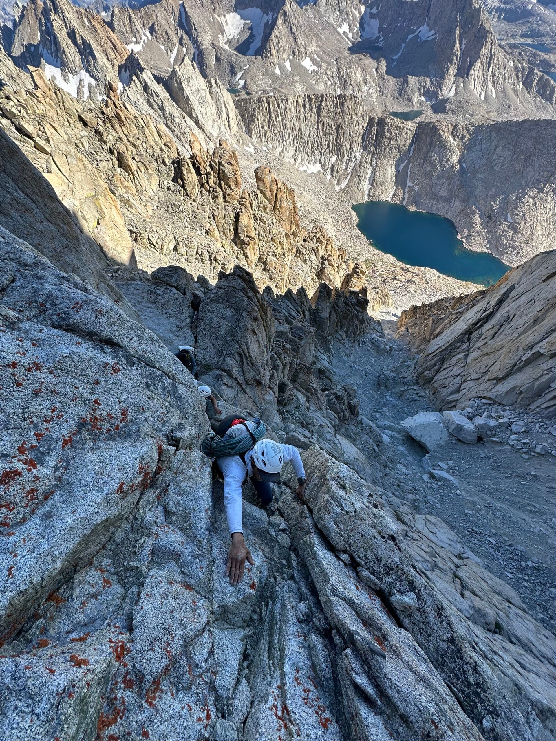 Two climbers in white helmets free solo on the world's longest rock climb.
