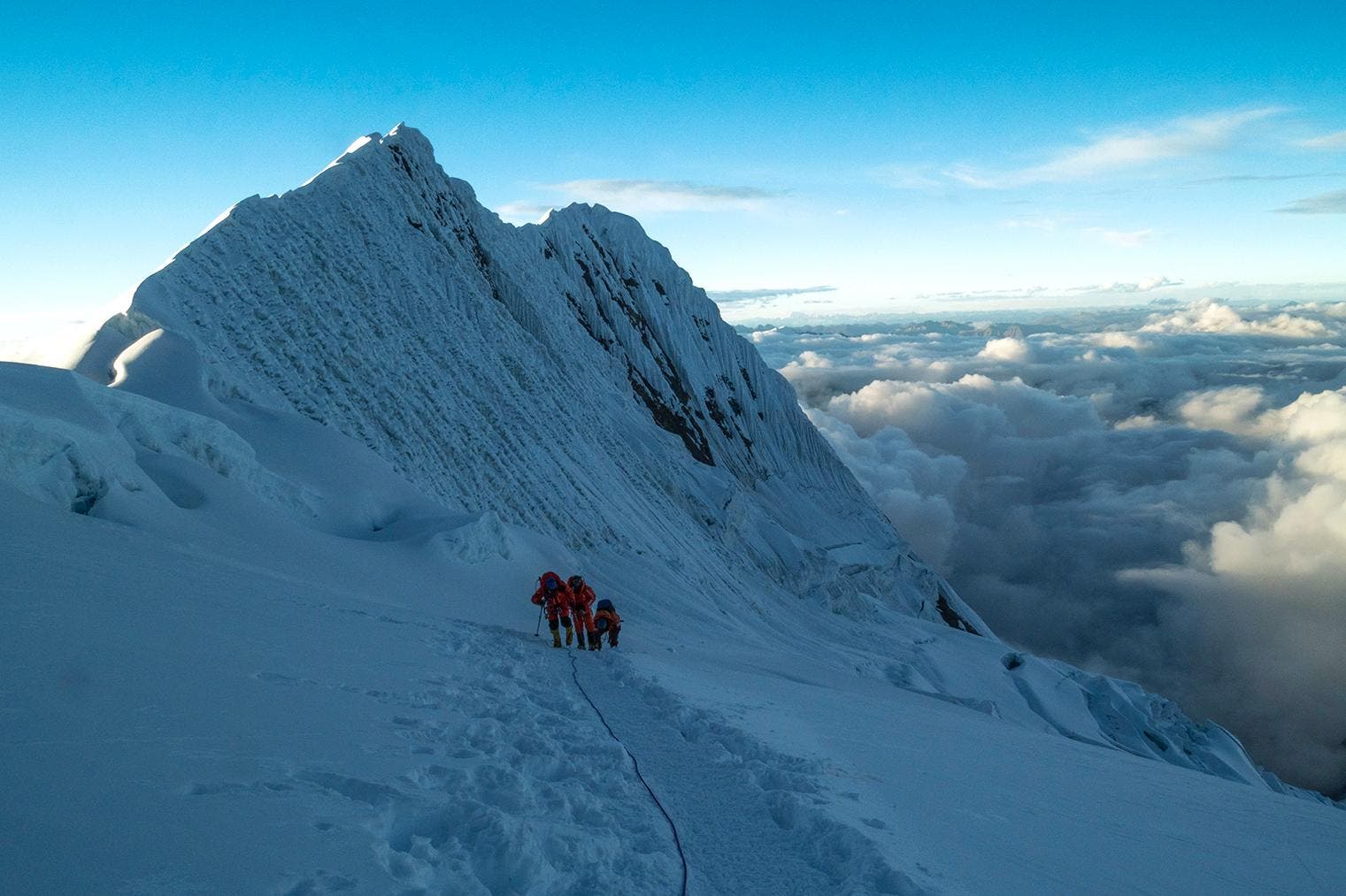 three climbers ascending a snowy mountain in nepal