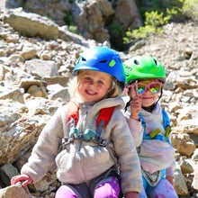 gifts for climber kids: 2 little girls wearing helmets near a scree field