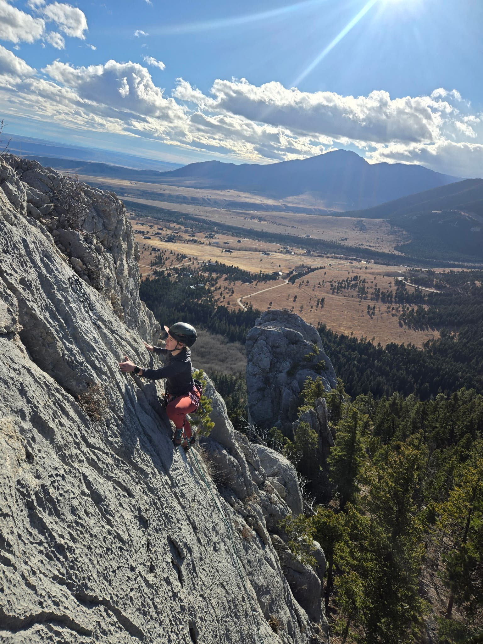 Ayla McNeilley climbs near the top of a route at the Palace, with the valley of Red Lodge, Montana visible behind her.