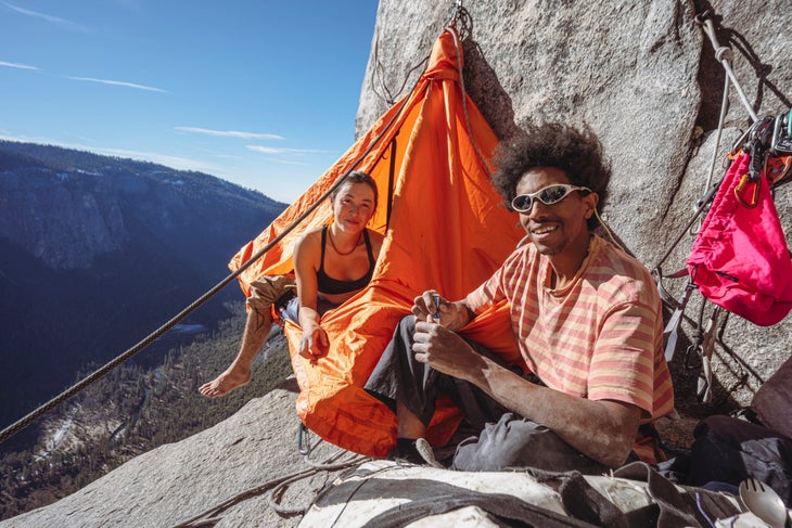 A female and male climber in an orange portaledge on El Capitan