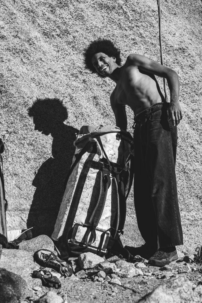 A climber reaching into a haul bag next to El Capitan