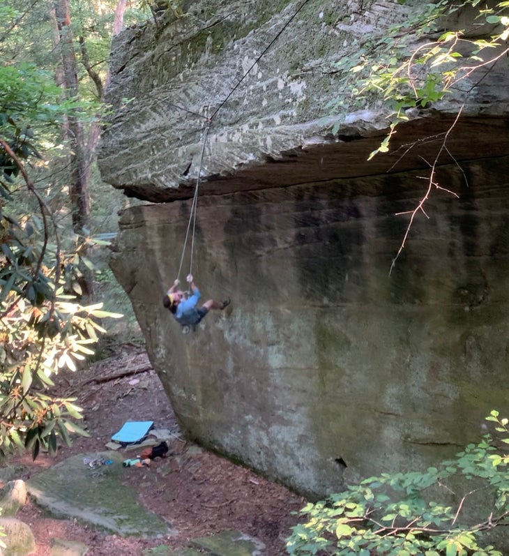 Climber hangs from rope below a large roof in West Virginia.