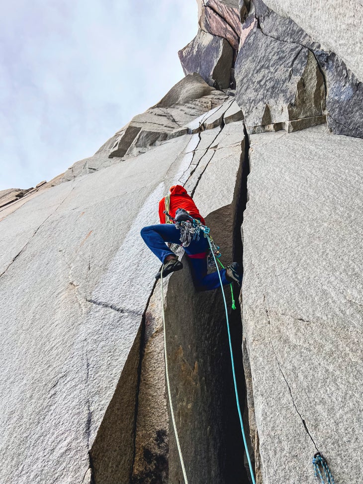 Man in red climbs granite crack in Patagonia.