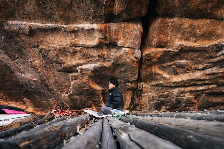 Beckett Hsin sits at the base of a boulder