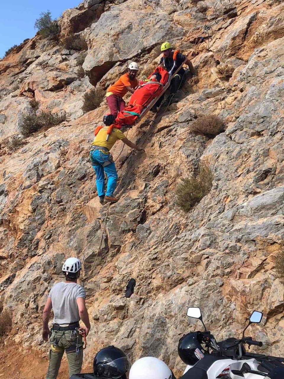 Rescuers guide a litter down a cliff line after a deadly sport climbing fall in Greece.